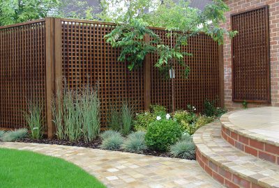 Fencing behind garden shrubs and paving