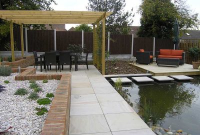 Table and chairs under pergola by pond